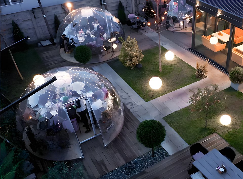 Giardino di un ristorante al crepuscolo con due bolle trasparenti apparecchiate
