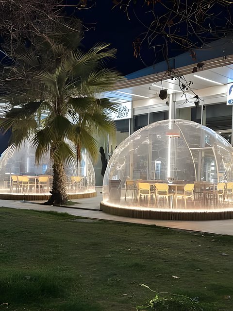 Bolla trasparente illuminata di sera accanto a una palma